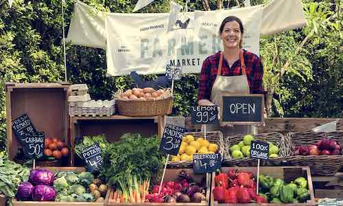 Greengrocer selling organic fresh agricultural product at farmer market - Shutterstock
